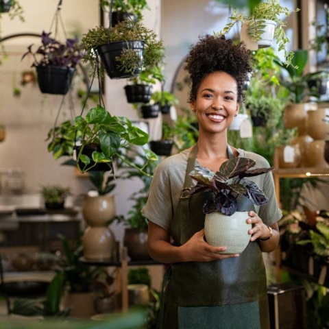woman holding plant insie a store with more plants surrounding her